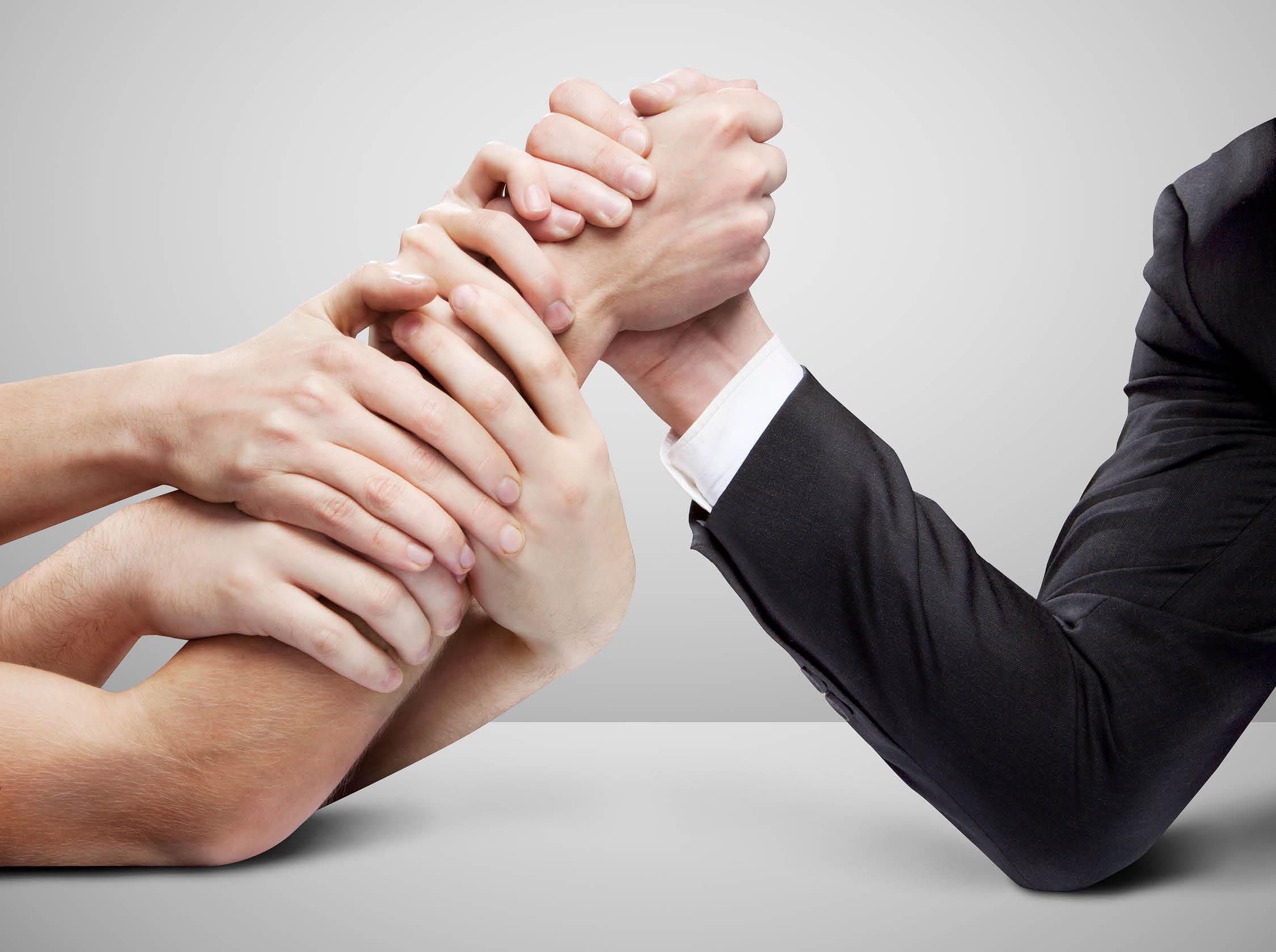 arm wrestling: businessman in opposition with many hands on gray background