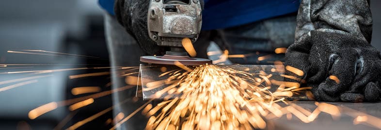Industrial worker cutting metal with many sharp sparks